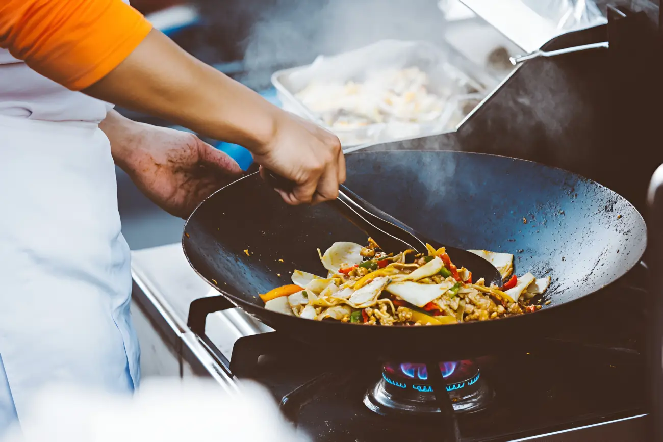 Kucharka mieszająca potrawę w woku