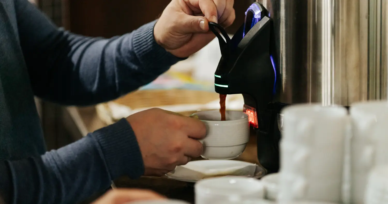 Mężczyzna nalewa ciepły napój z termosu gastronomicznego