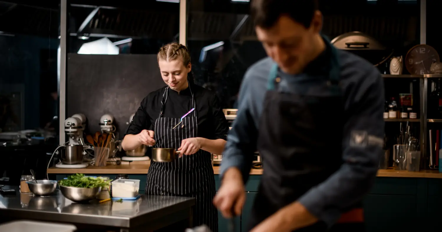 Kucharka i kucharz gotujący w profesjonalnej kuchni
