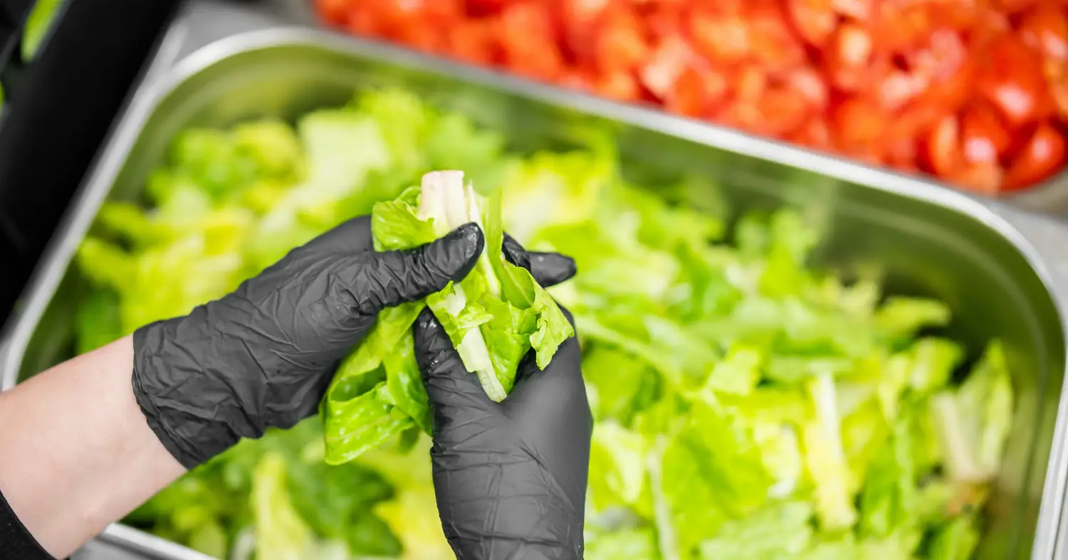 Kucharz przygotowuje warzywa do pojemnika gastronomicznego