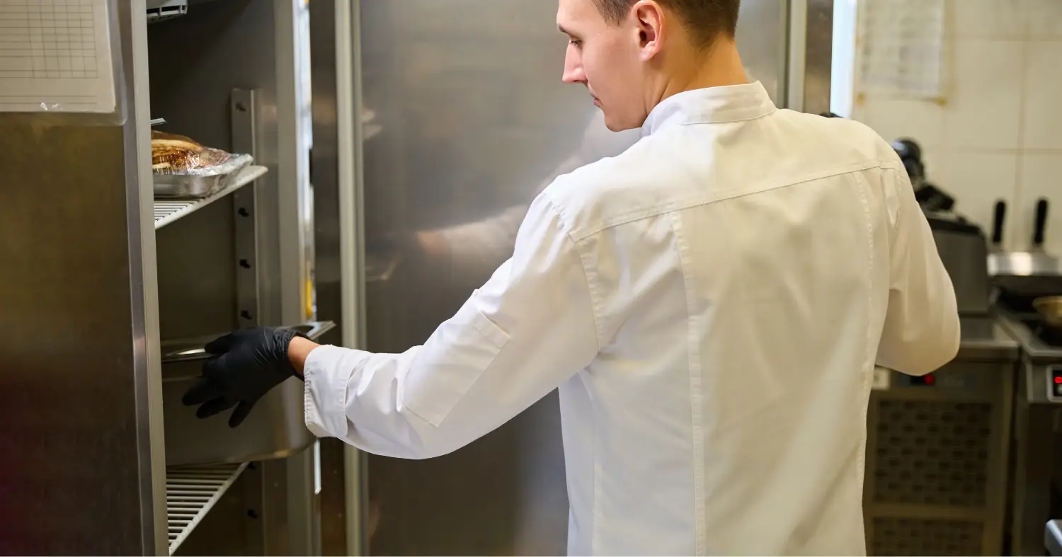 kucharz wkładający pojemnik do lodówki