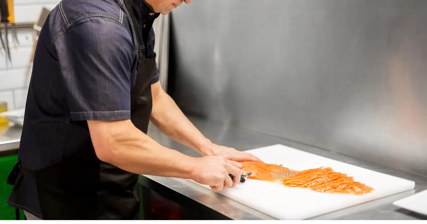 kucharz przygotowuje wędzonego łososia