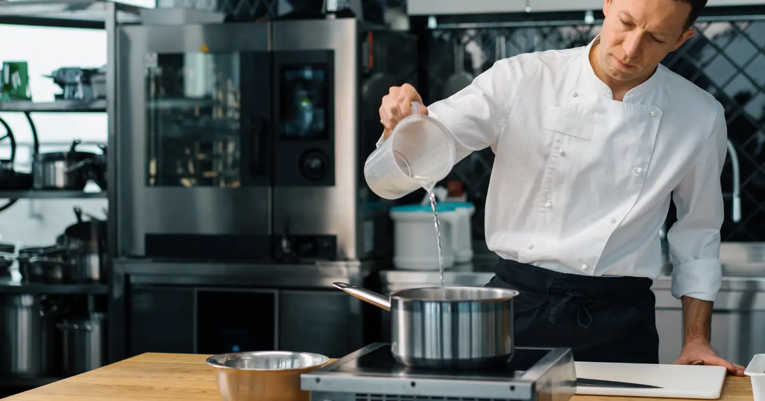 szef kuchni odmierza wodę do potrawy 