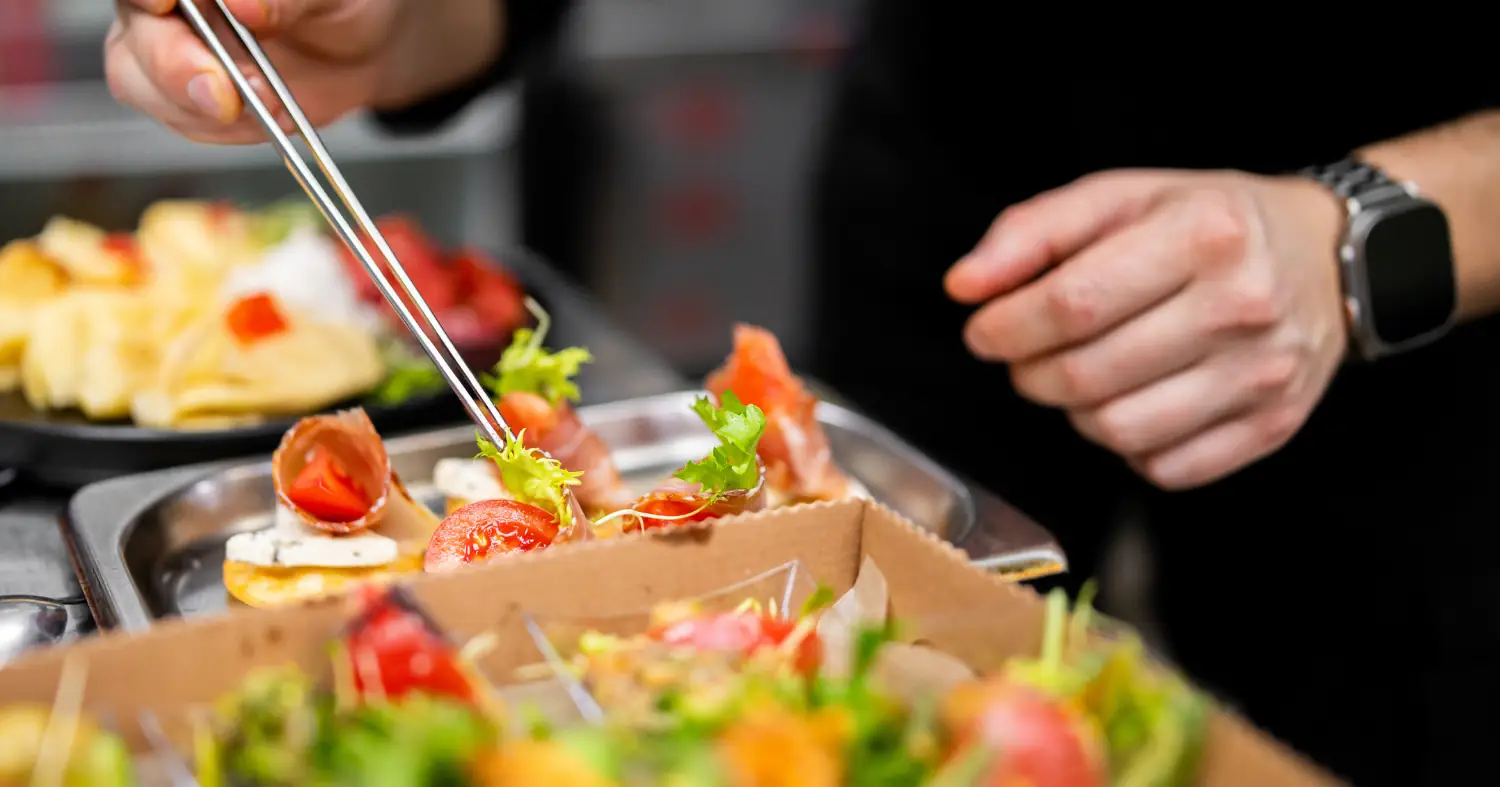 kucharz dokańcza danie na wynos w papierowych pudełkach 