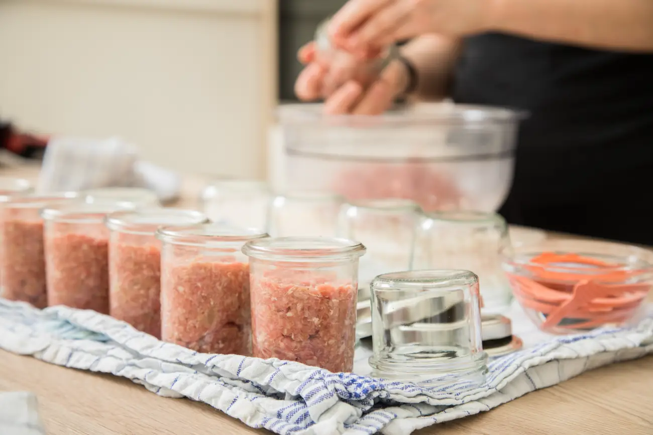 Osoba wsadzająca mięso do słoików w celu sterylizacji