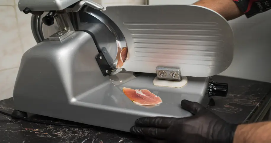 Osoba krojąca włoską wędlinę na krajalnicy