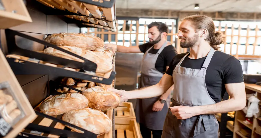 Pracownicy piekarni biorący chleby z półki