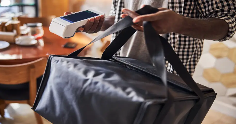 Mężczyzna z torbą na pizzę i terminalem