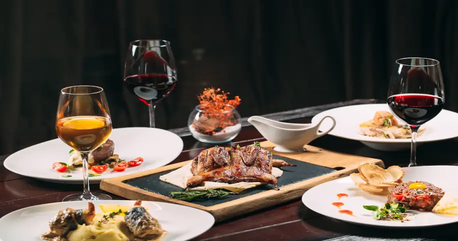Dania mięsne oraz kieliszki z białym i czerwonym winem