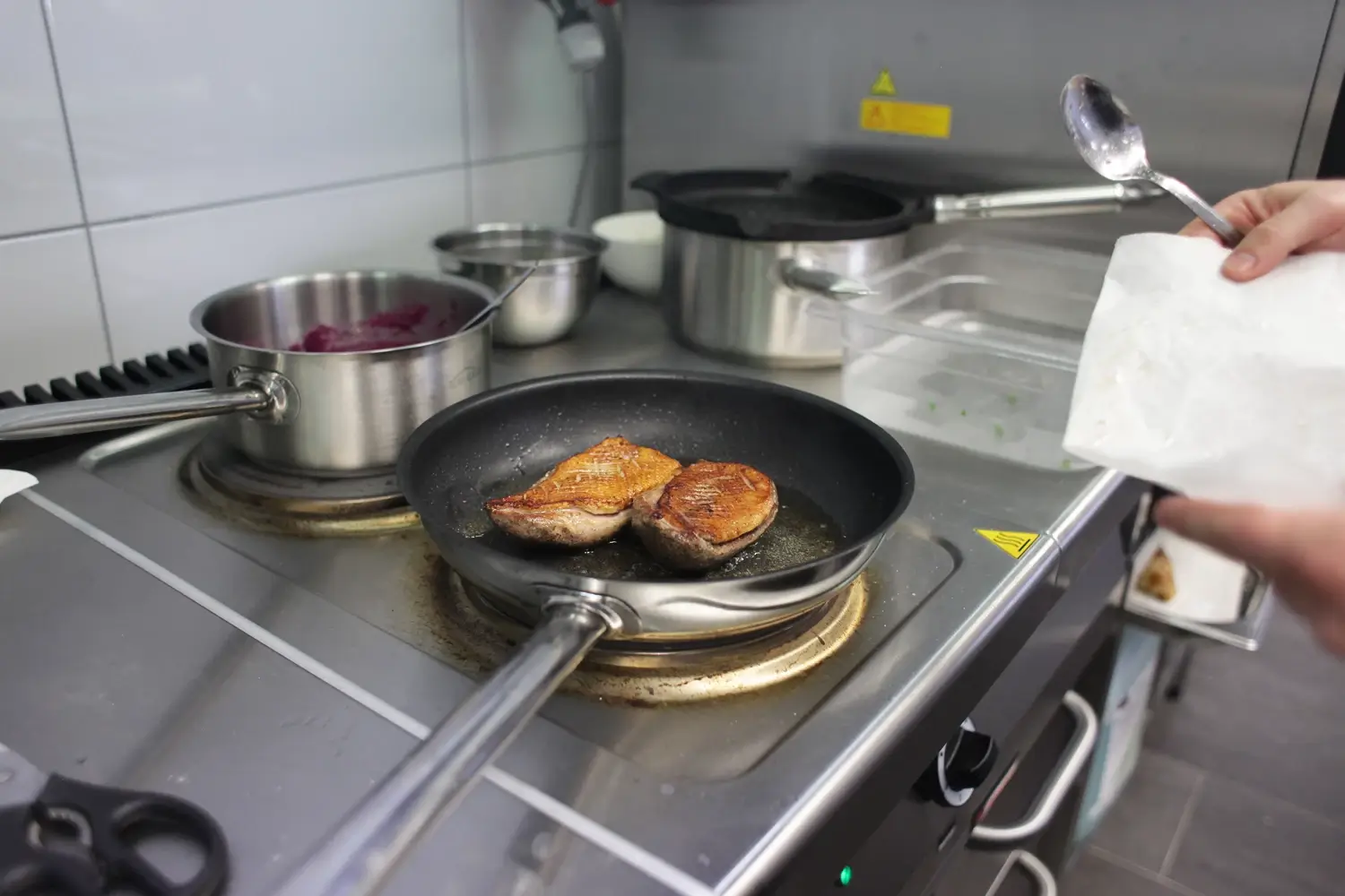 Przygotowywanie piersi z kaczki na patelni w profesjonalnej kuchni gastronomicznej.