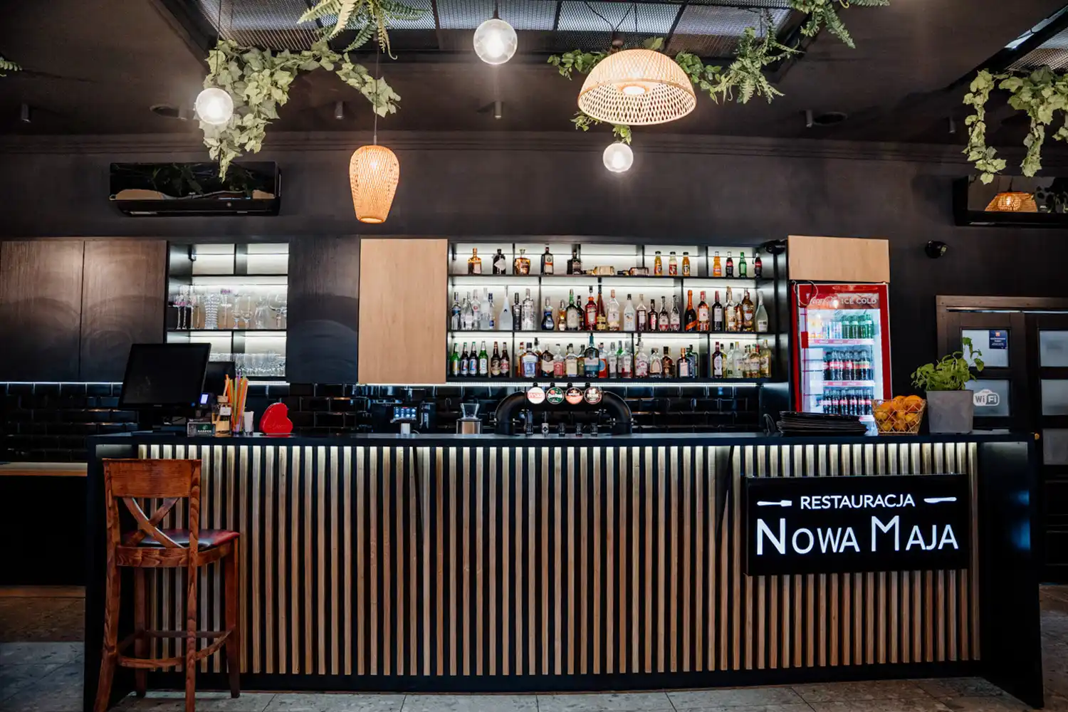 Wnętrze restauracji Nowa Maja w Skoczowie – widok na bar z podświetlanym szyldem i zapleczem barowym.