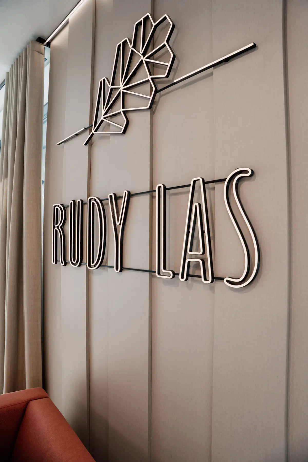 Podświetlane logo restauracji Rudy Las z motywem liścia, umieszczone na ścianie we wnętrzu lokalu.
