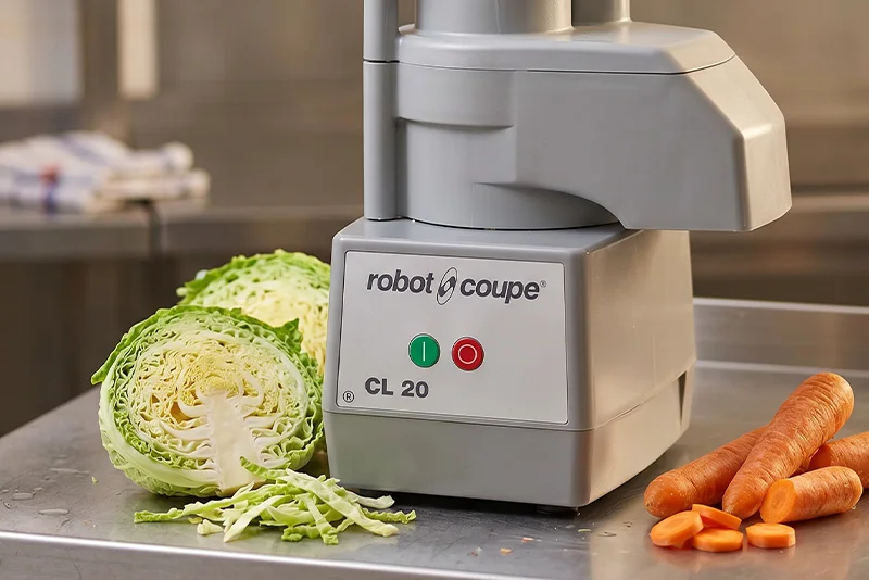 Profesjonalna szatkownica do warzyw Robot Coupe CL 20 stojąca na stalowym blacie.
