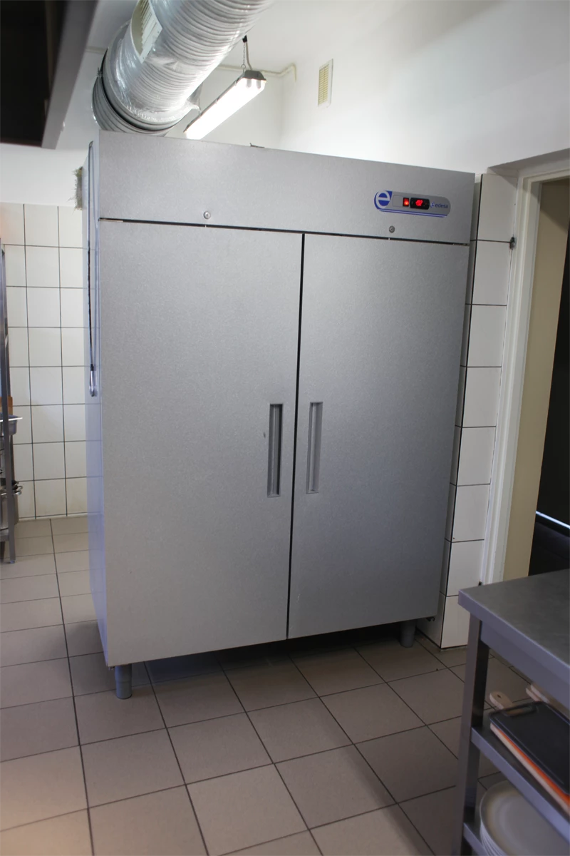 Dwudrzwiowa szafa chłodnicza ze stali nierdzewnej w kuchni gastronomicznej.