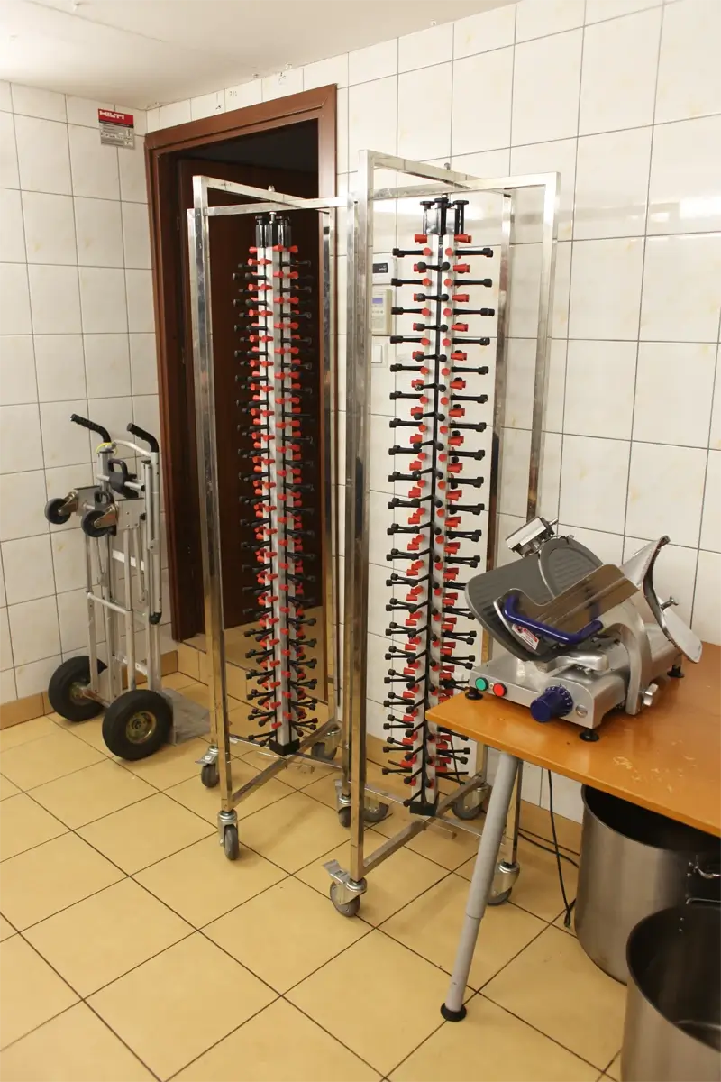 Magazyn kuchenny z wózkiem transportowym, wózkiem na pojemniki GN, stojakiem na pokrywki i krajalnicą gastronomiczną.