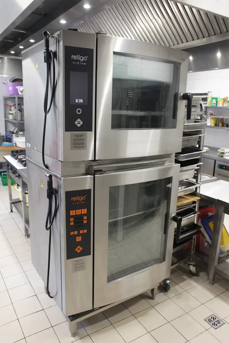 Dwa nowoczesne piece konwekcyjno-parowe Retigo Vision ustawione jeden na drugim w kuchni gastronomicznej.