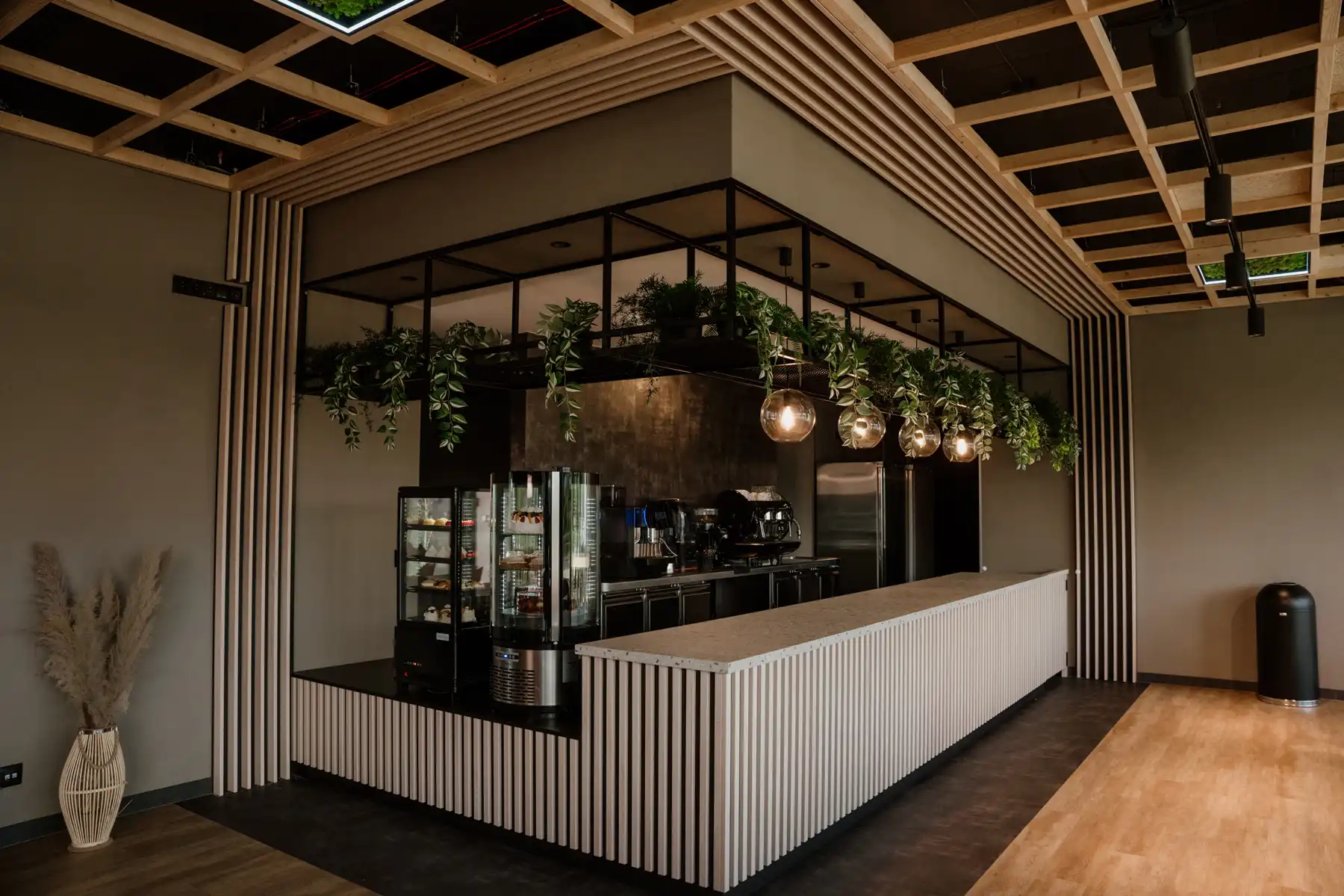 Nowoczesny bar kawowy z zabudową drewnianą i zielenią, zaprojektowany do profesjonalnej obsługi gastronomicznej.