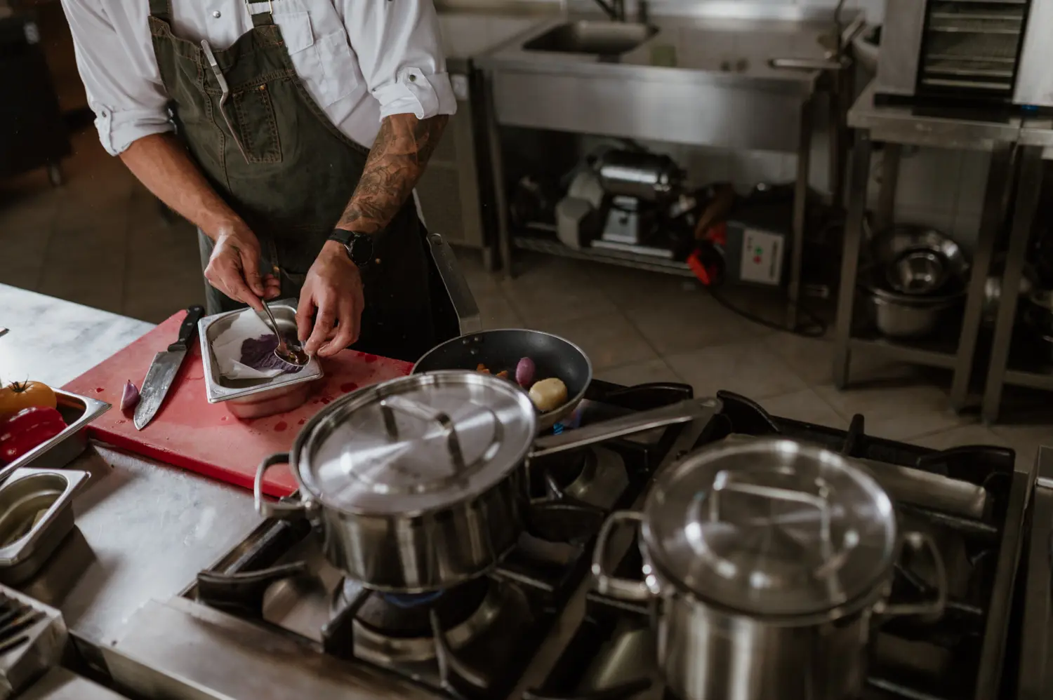 Szef kuchni przygotowujący danie przy kuchence gazowej w profesjonalnej kuchni gastronomicznej.