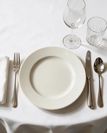 Porcelanowy talerz BONNA  w eleganckim nakryciu stołu restauracyjnego z białym obrusem, sztućcami i szkłem.